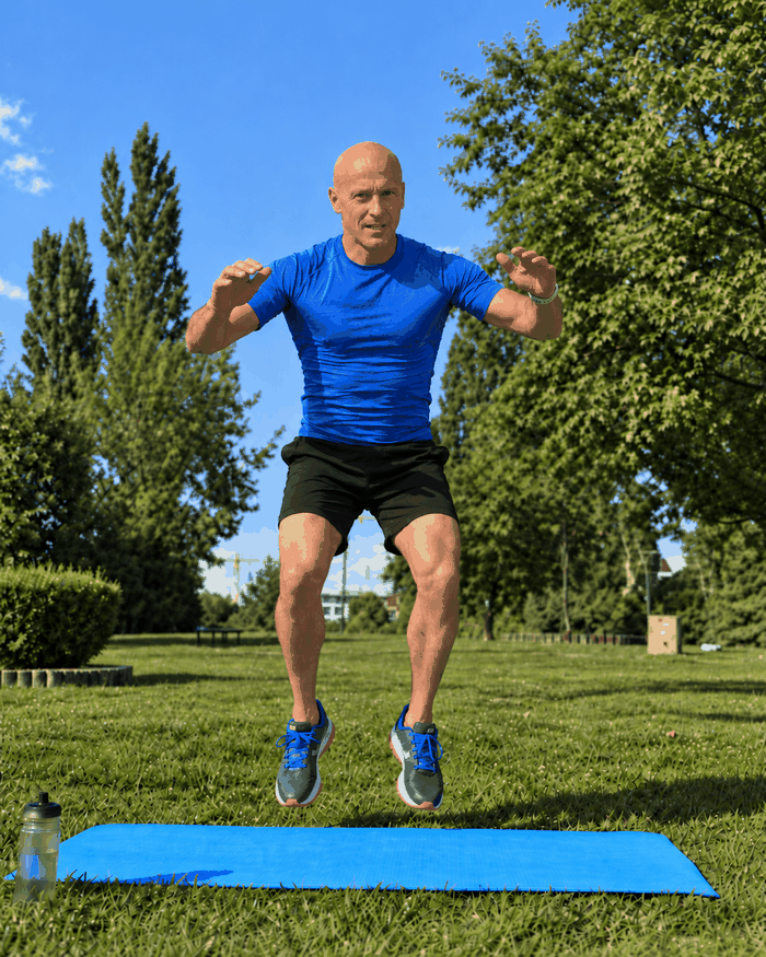 Man performing the jump phase of an advanced burpee outdoors