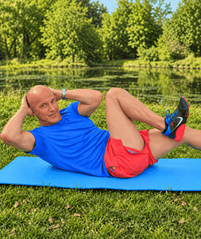 Man performing a bicycle crunch outdoors by a lake