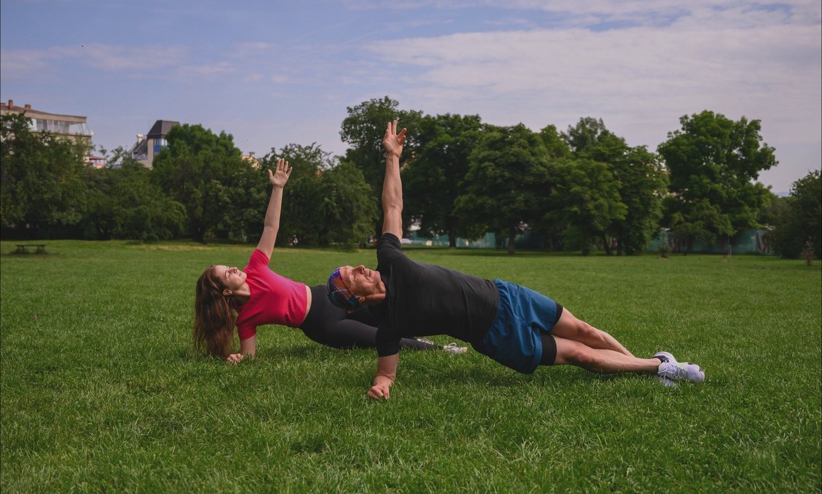 Father and daughter performing side plank exercises outdoors